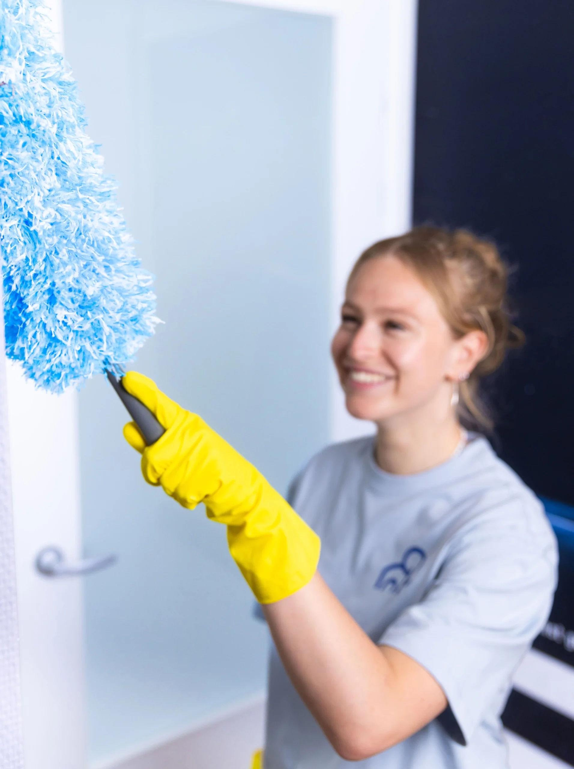 een vrouw die een huis schoonmaakt met een blauwe stoffer