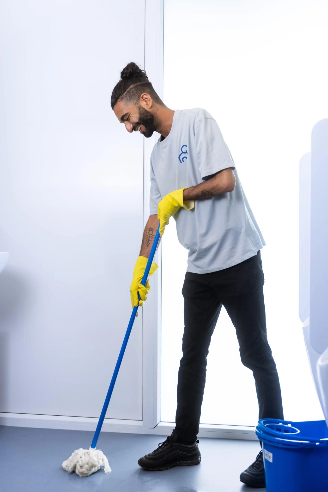 een medewerker van clean and clever die de sanitair dweilt met een blauwe dweil en gele handschonen